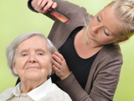 caregiver assisting senior woman in combing her hair